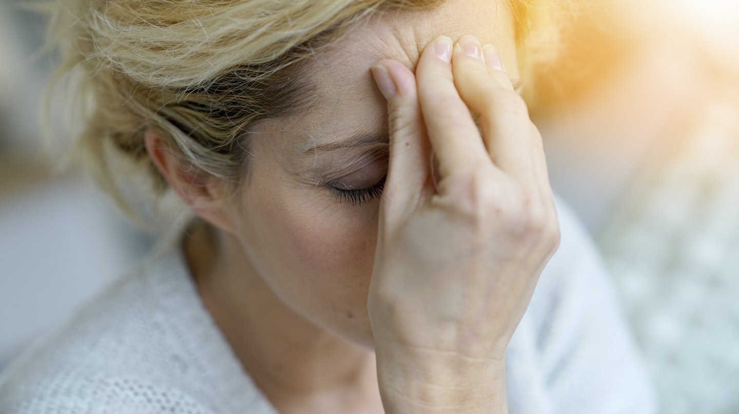 Migräne: Eine Frau mit geschlossenen Augen drück die Finger einer Hand an die Stirn.